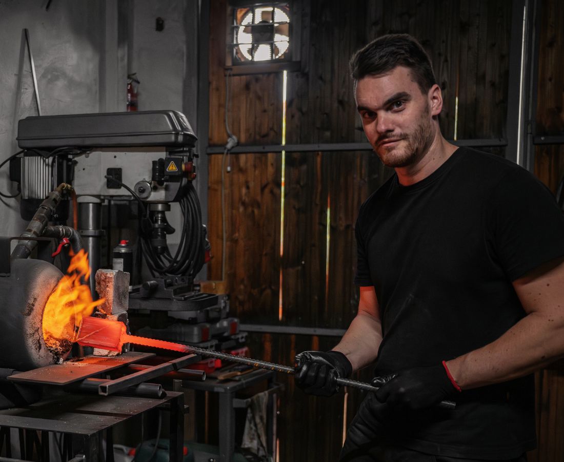 Dies ist ein Foto, dass einen Schmied bei der Arbeit zeigt. Es handelt sich um den Besitzer der Messerschmiede Jettenbach, der handgemachte Damastmesser als Küchenmesser und Jagdmesser anbietet.