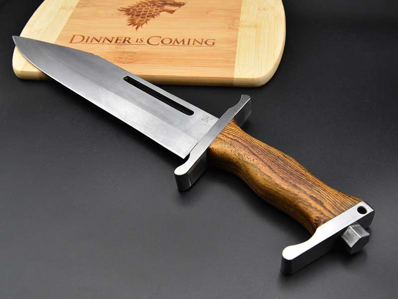 Dies ist ein Foto eines hangemachten Jagdmessers der Messerschmiede Jettenbach. Dieses liegt auf einem Holzbrett im Game of Thrones Stil.